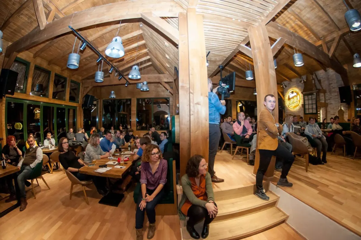 Sala plină în timpul unui eveniment, sub grinzile de lemn